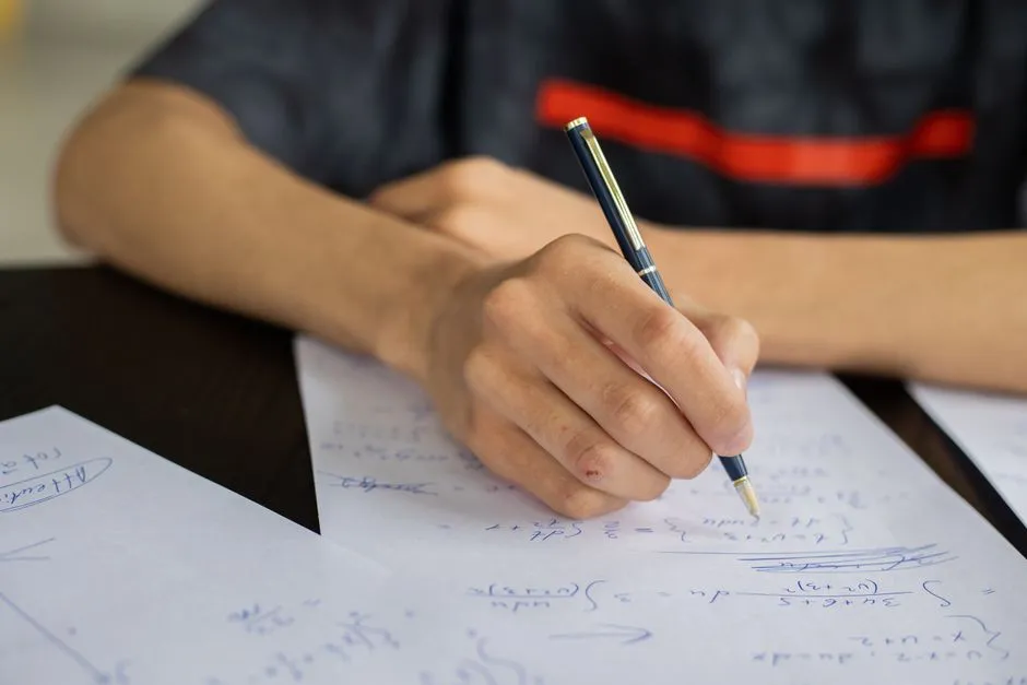 Student writing out worked math problems while studying